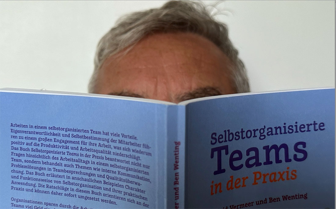 Mann liest in Buch Selbstorganisierte Teams in der Praxis